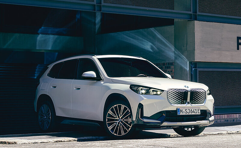 Ein weißer BMW iX fährt aus einem Parkhaus