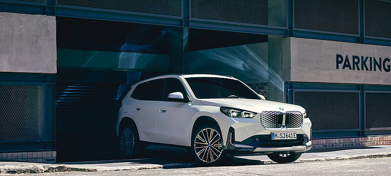 Ein weißer BMW iX fährt aus einem Parkhaus